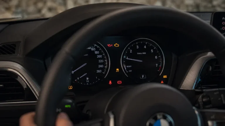 Tableau de bord de BMW Série 1 affichant plusieurs voyants d’alerte moteur, ABS, pression d’huile et pneus.