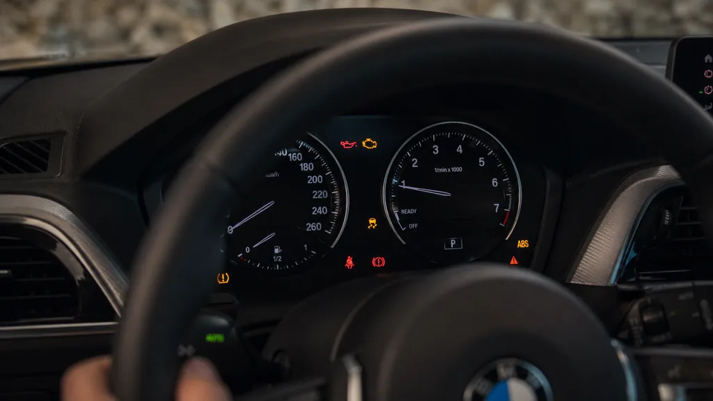 Tableau de bord de BMW Série 1 affichant plusieurs voyants d’alerte moteur, ABS, pression d’huile et pneus.