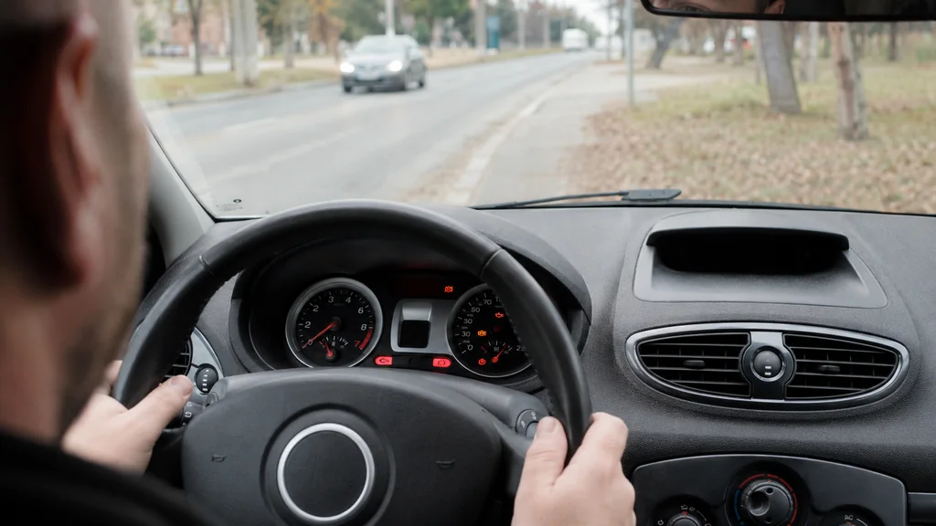 Conducteur observant les voyants rouges et orange allumés sur le tableau de bord d’une Renault Clio 3 arrêtée sur le bord de la route.