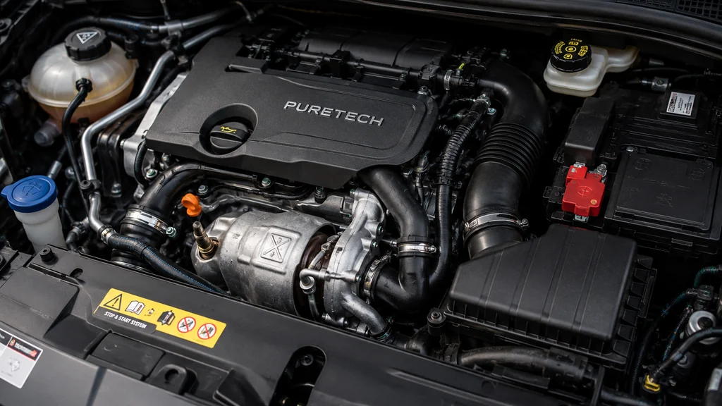 Moteur PureTech visible sous le capot d’une voiture avec ses composants mécaniques.