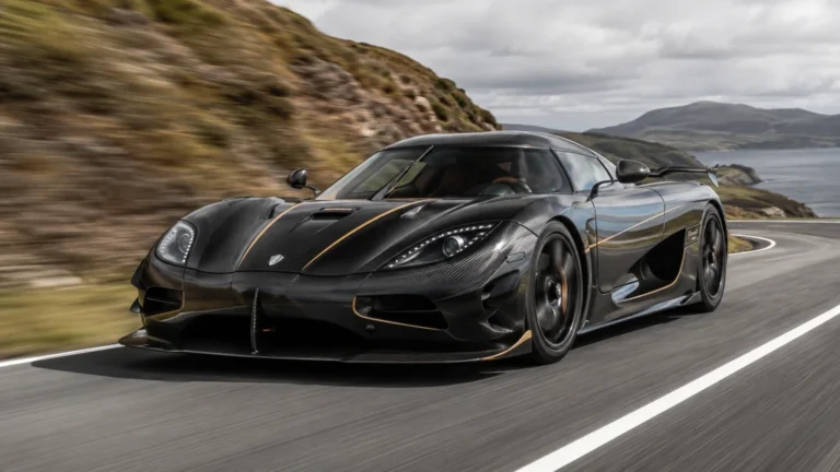 Koenigsegg Agera noire roulant à grande vitesse sur une route côtière sinueuse