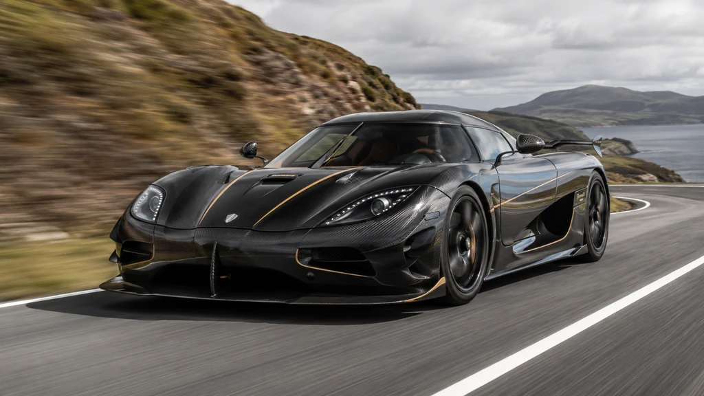 Koenigsegg Agera noire roulant à grande vitesse sur une route côtière sinueuse